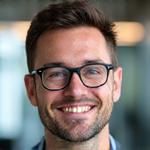 Portrait of Marc Schmidt, a smiling man with short hair and glasses, wearing business casual.